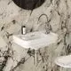 Waschbecken mit integrierter Armatur in Chrom, auf marmoriertem Wanddesign. Aus einer Ideal Standard Kollektion, kombiniert Funktionalität und modernes Design.
